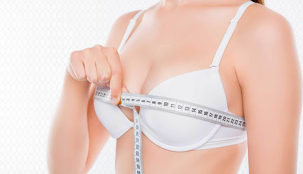 Woman measuring breast size before undergoing breast reduction procedure